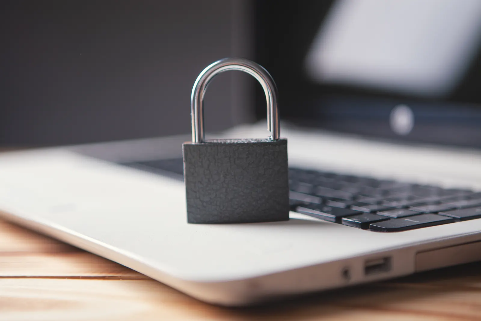 A grey padlock resting on an open laptop keyboard