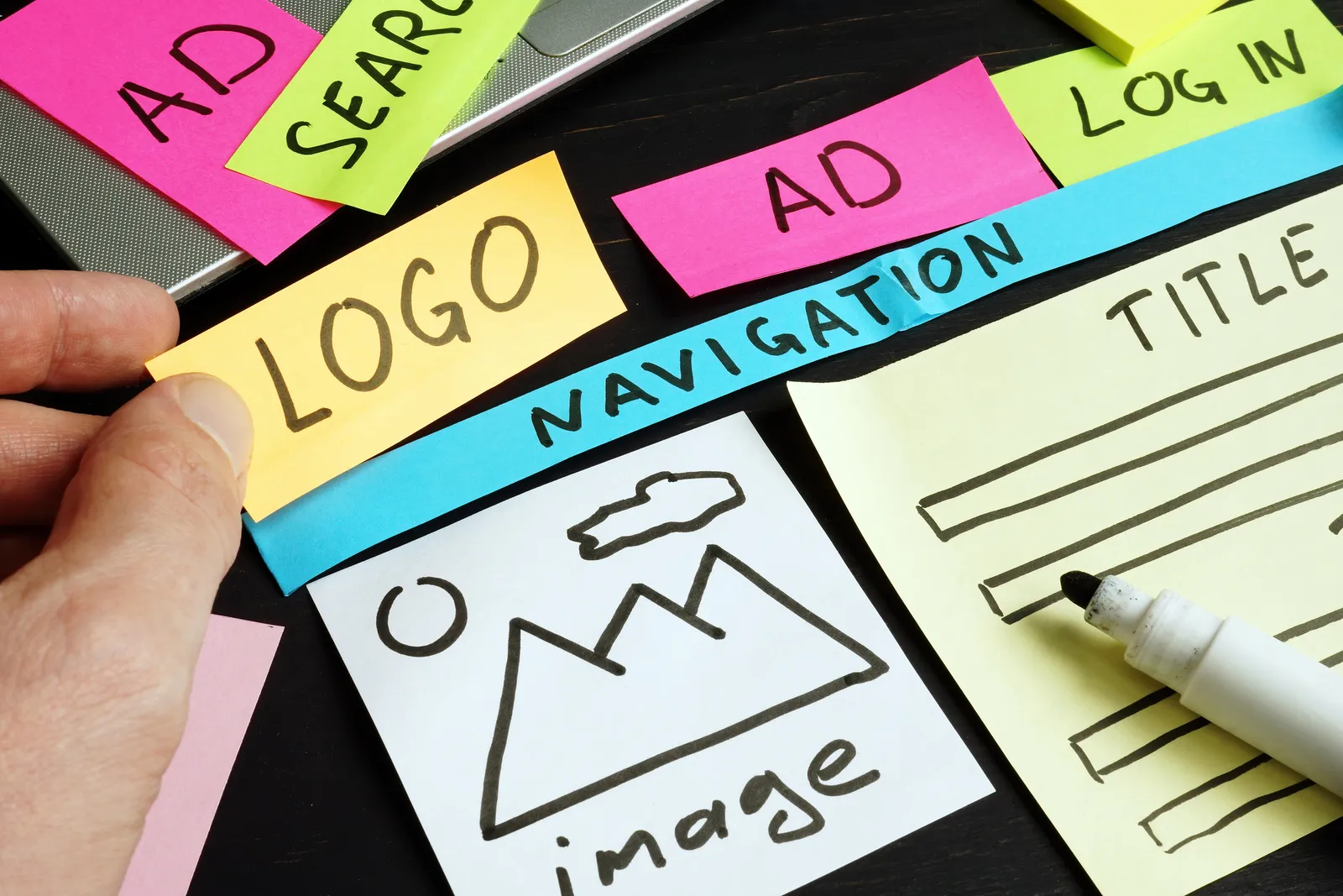 Hand-drawn website layout on colorful sticky notes: logo, navigation, search and an image box